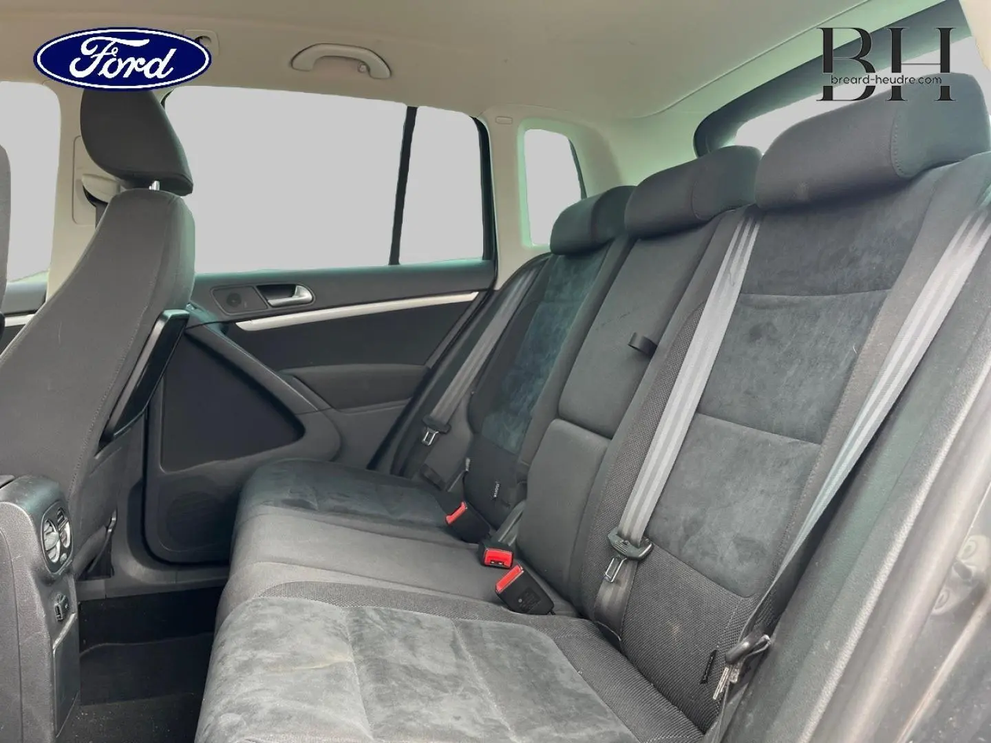 Vue intérieure côté droit de la banquette arrière grise du Volkswagen Tiguan 2014 avec ceintures et appuie-têtes visibles.
