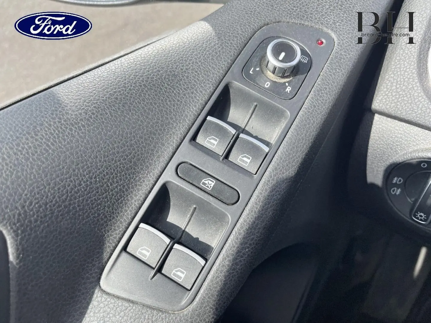 Panneau de commandes des vitres électriques et réglage des rétroviseurs côté conducteur d’un véhicule, avec logo Ford visible.