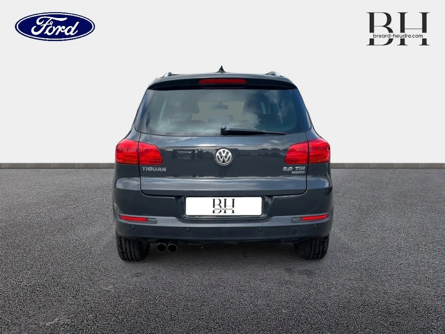 Vue arrière d'un Volkswagen Tiguan gris poivre avec double sortie d'échappement et feux rouges allongés.