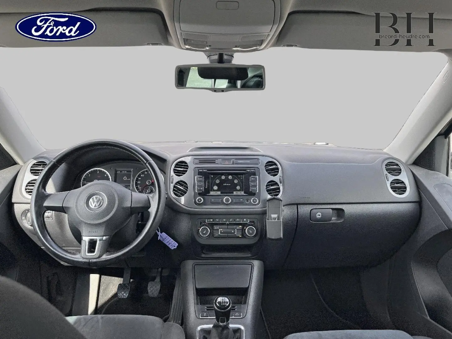 Vue intérieure frontale du tableau de bord noir et volant cuir du Volkswagen Tiguan 2014 avec boîte manuelle.