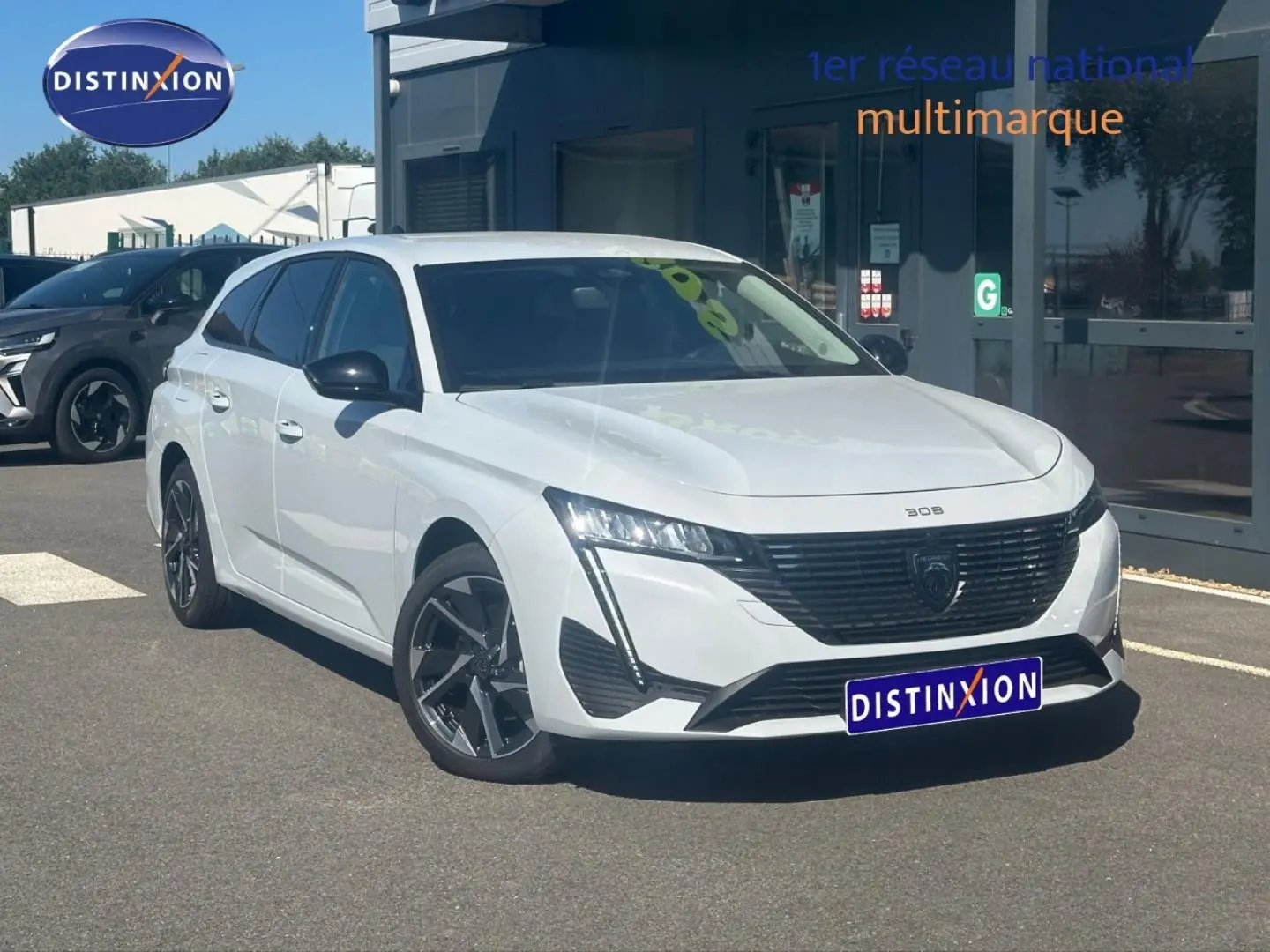 Peugeot 308 SW blanc Okénite vue 3/4 avant droit, avec jantes alliage et calandre noire distinctive.