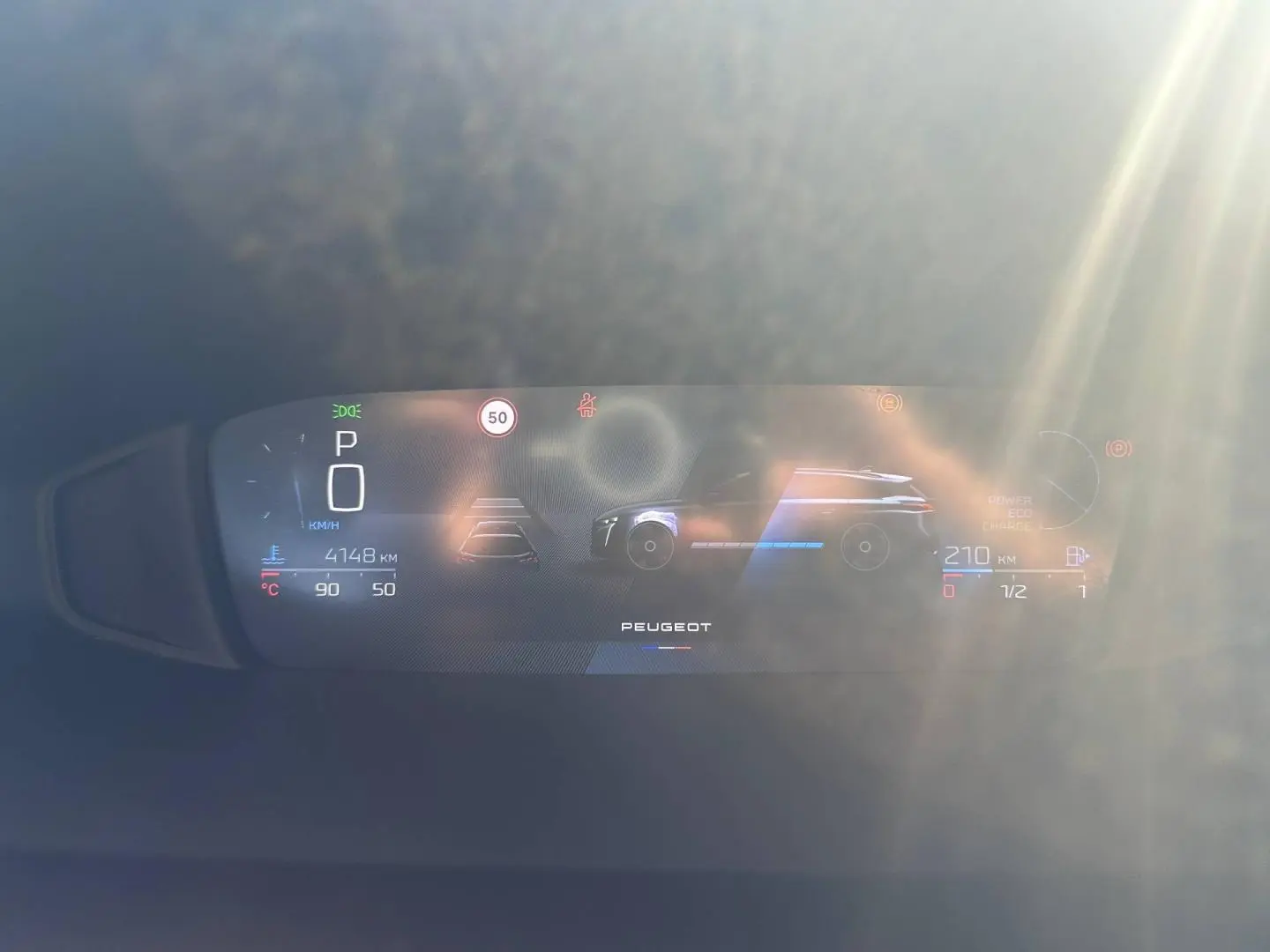 Tableau de bord numérique du Peugeot 308 SW hybride, affichant la vitesse, autonomie et indicateurs, avec reflet lumineux.