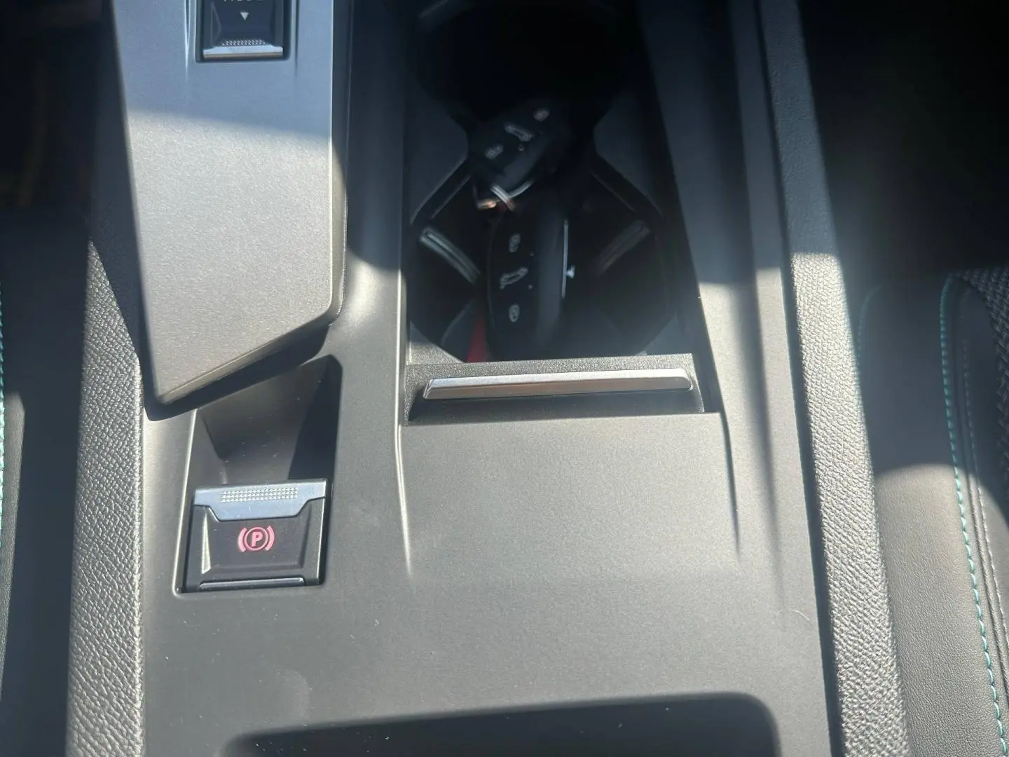 Gros plan sur la console centrale de la Peugeot 308 SW blanche, avec frein à main électrique et porte-clés visible.