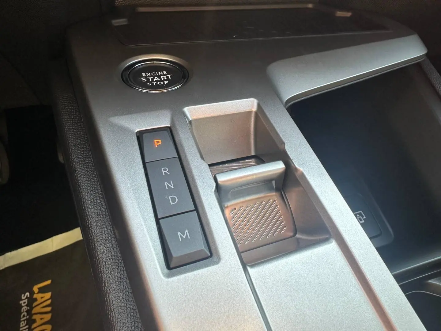 Gros plan sur la console centrale grise de la Peugeot 308 SW Hybrid avec bouton start/stop et commandes de boîte automatique.