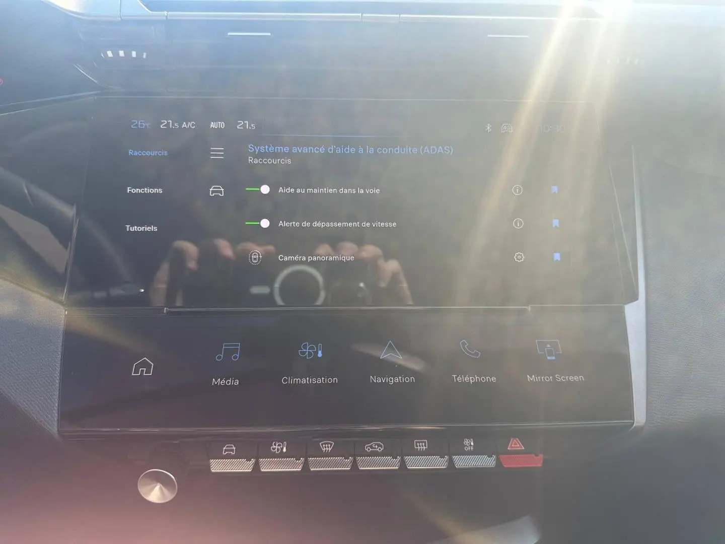 Écran tactile central du Peugeot 308 SW 2025 montrant les aides à la conduite, avec reflets lumineux.