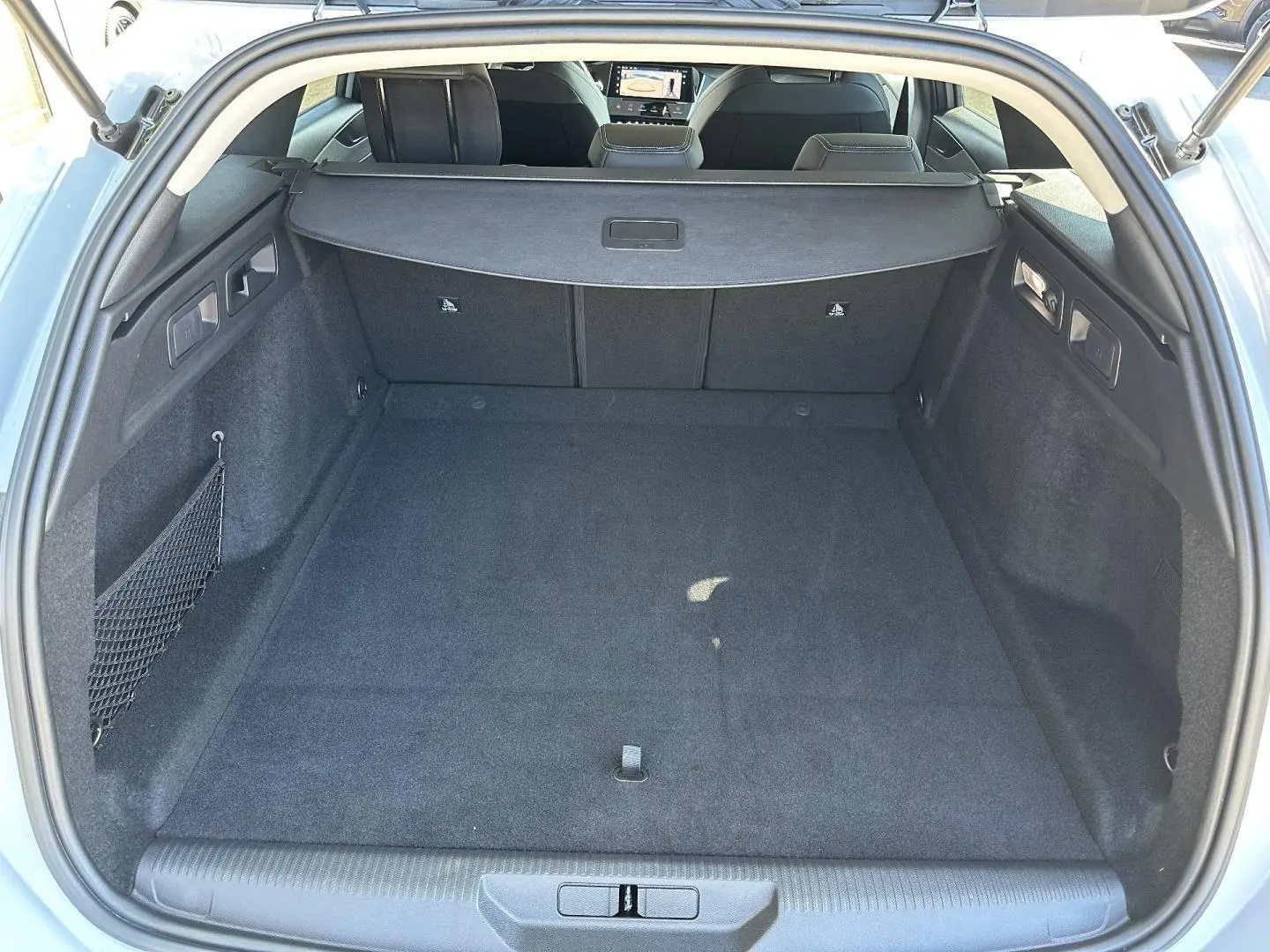 Vue intérieure du coffre spacieux et propre de la Peugeot 308 SW blanc Okénite, avec cache-bagages déployé.