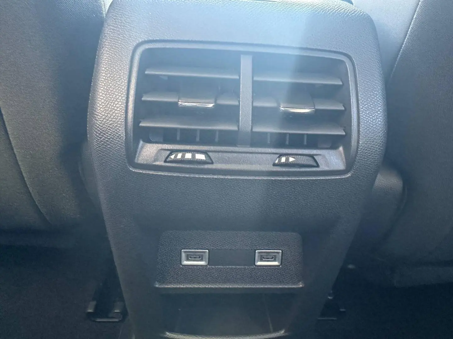 Vue rapprochée de la console arrière noire avec bouches d'aération et deux ports USB du Peugeot 308 SW blanc Okénite.