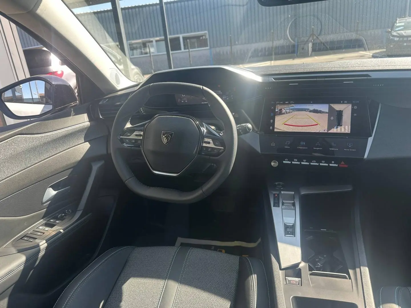 Vue intérieure avant de la Peugeot 308 SW blanche, avec volant multifonction et écran tactile affichant la caméra de recul.