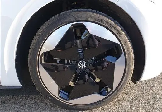 Gros plan sur la roue avant gauche du Volkswagen ID.3 blanc glacier, mettant en valeur la jante noire et argentée au design moderne.