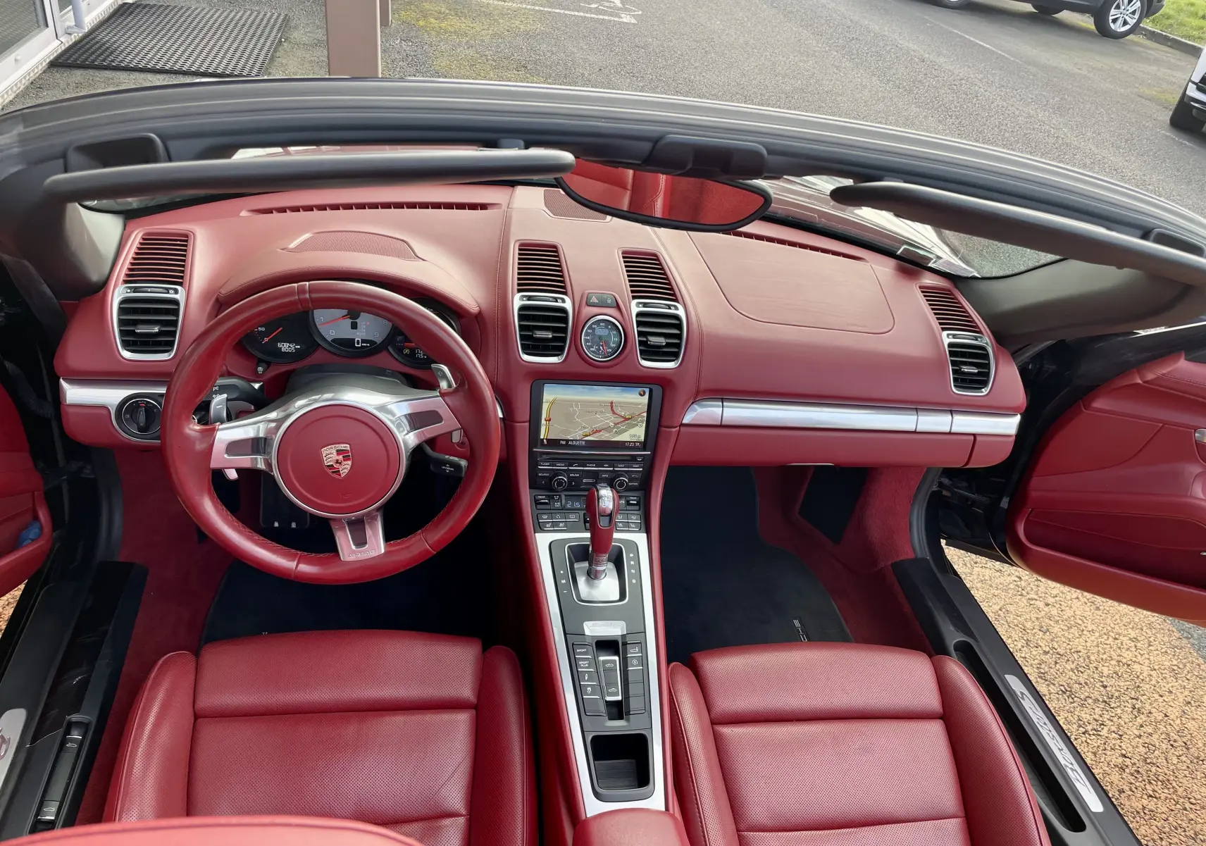 Vue intérieure avant de la Porsche Boxster S 981 2012 avec tableau de bord et sièges en cuir rouge grenat.