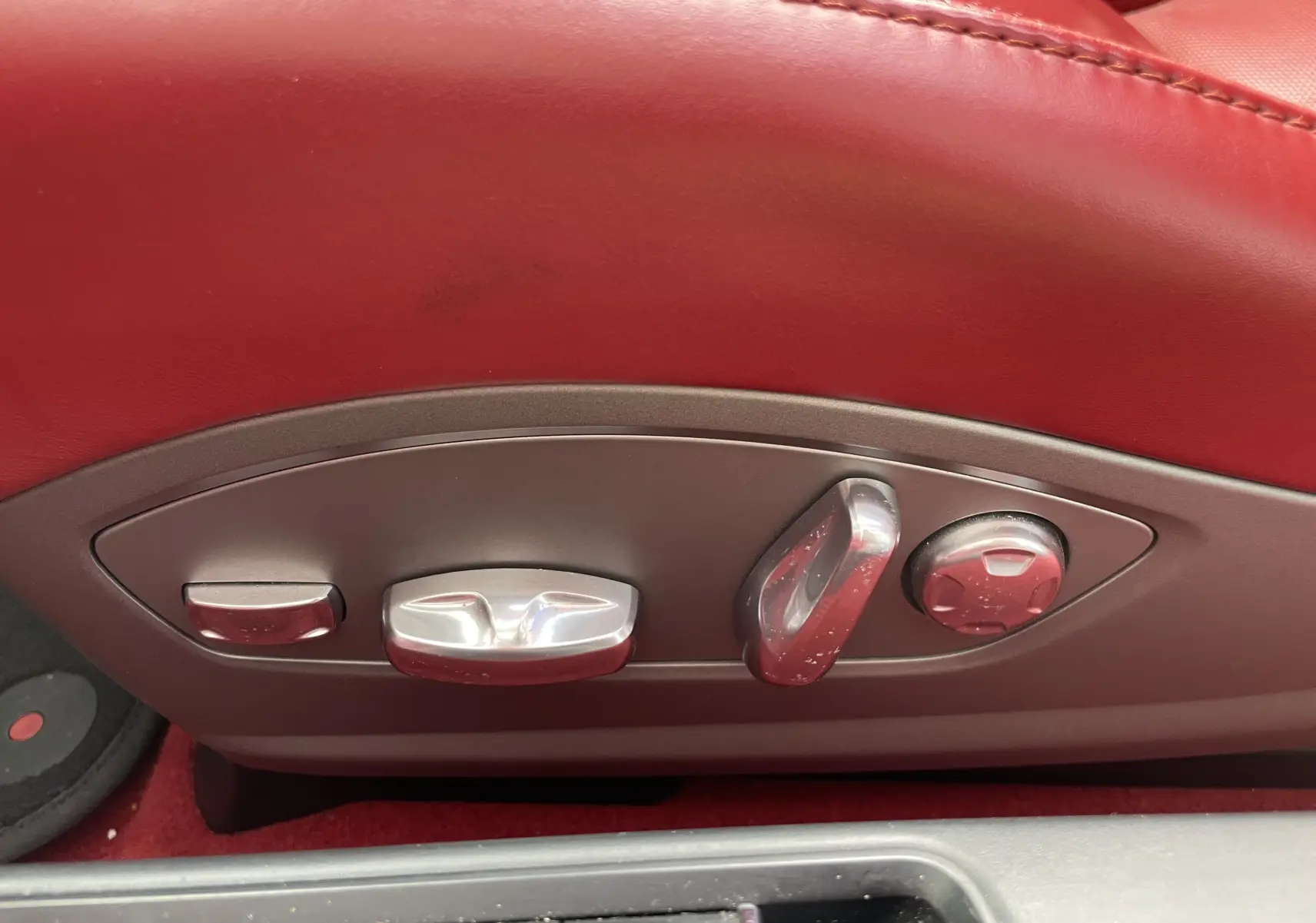 Gros plan sur les commandes électriques des sièges en cuir rouge grenat d'une Porsche Boxster S 2012