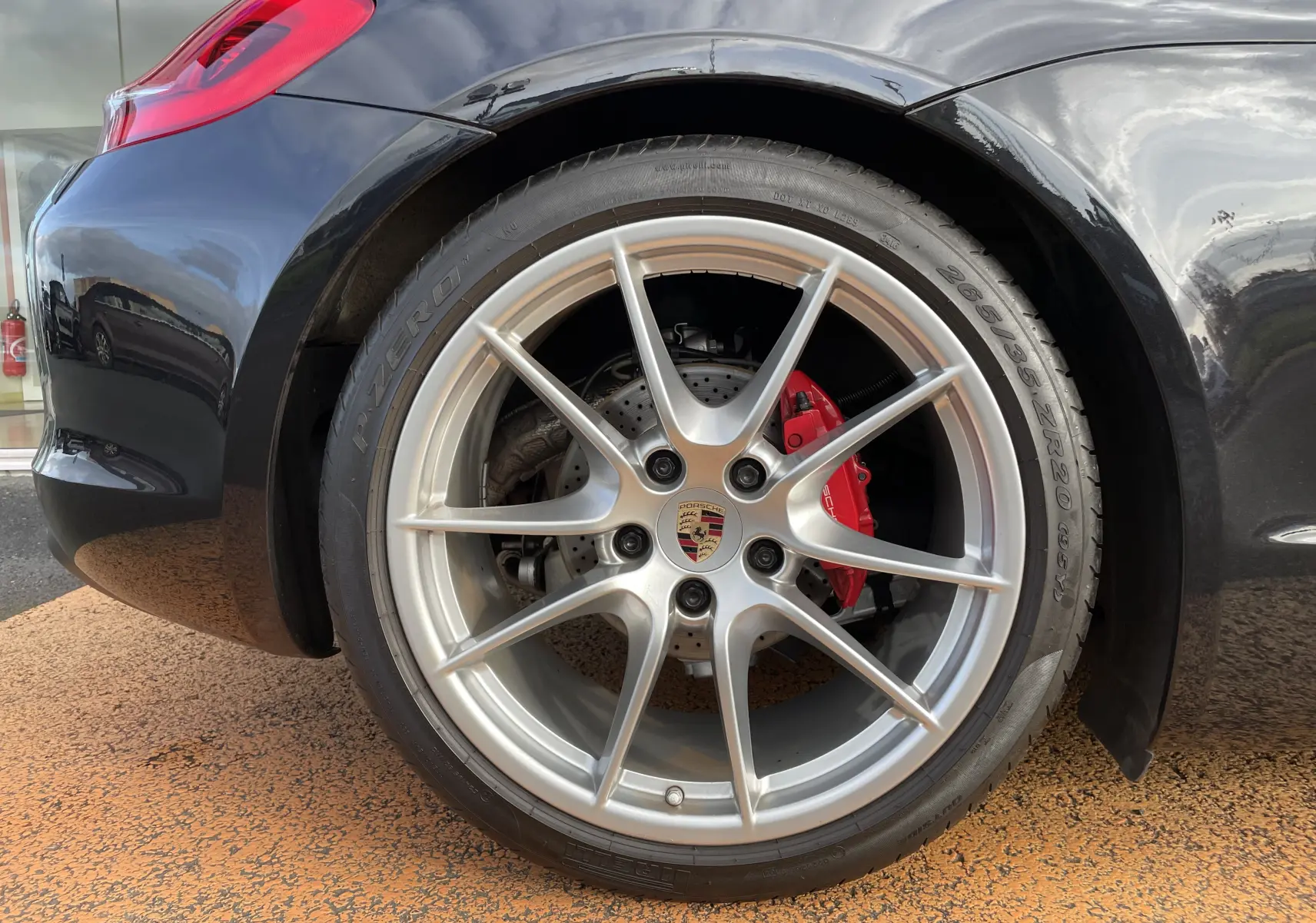 Gros plan sur la jante avant droite argentée avec logo Porsche et étrier de frein rouge sur Boxster S noir intense 2012.