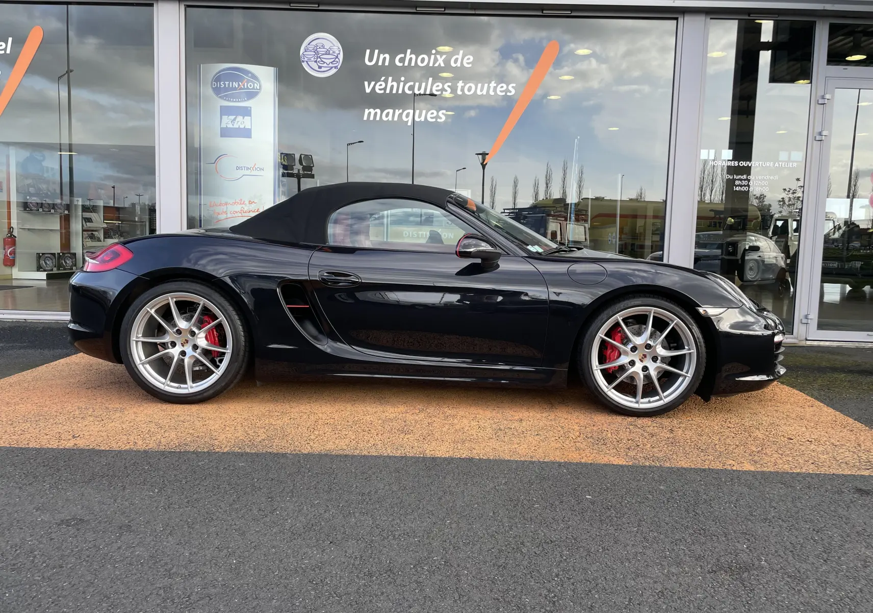 Profil latéral droit d'une Porsche Boxster S 981 noire intense avec capote noire et jantes Carrera S 20 pouces argentées.