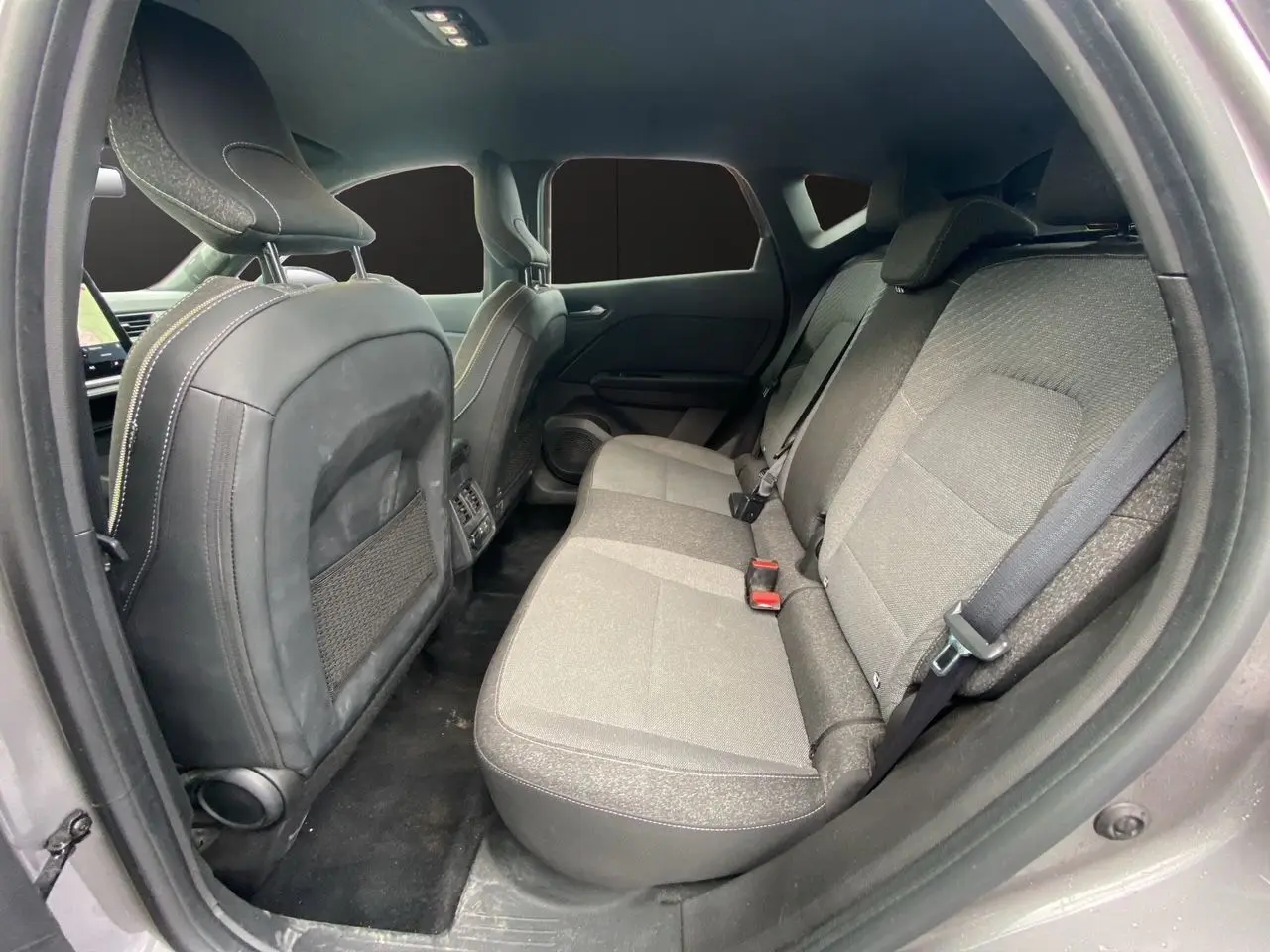 Vue intérieure arrière du Renault Captur 2025, sièges tissu gris et noir avec ceinture de sécurité visible.