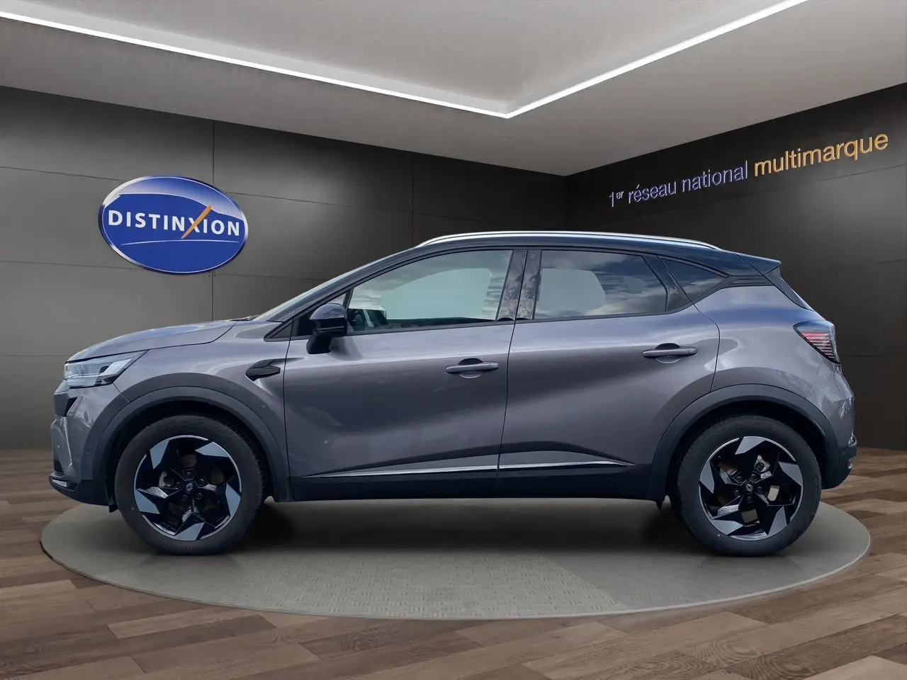 Profil côté gauche du Renault Captur gris Cassiopée avec toit noir, jantes alu 18 pouces et barres de toit visibles.