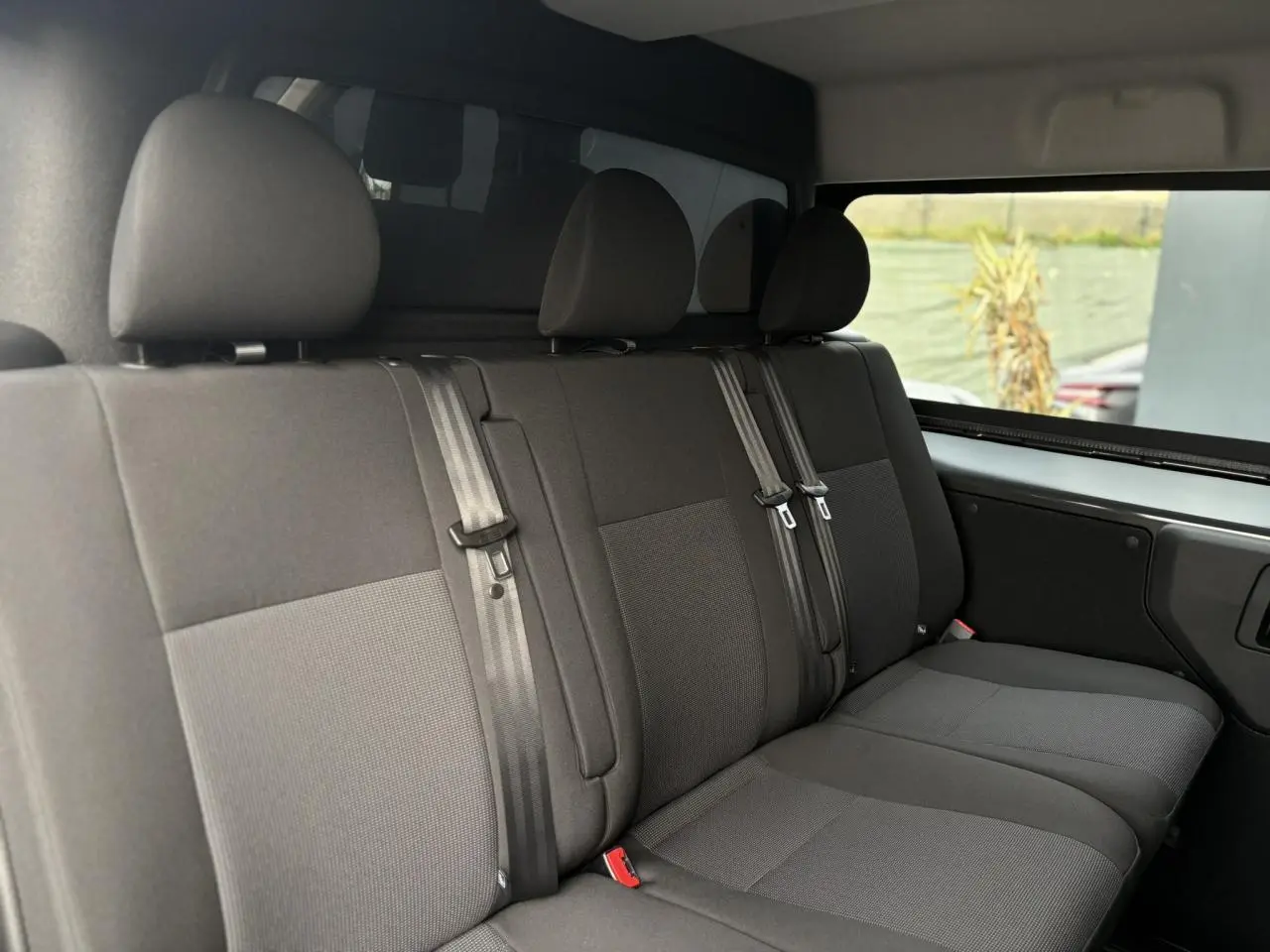 Vue intérieure de la banquette arrière 3 places en tissu bi-ton gris du Citroën Jumpy XL 2025, avec appuie-têtes et ceintures visibles.