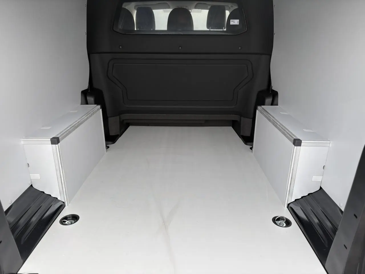 Vue arrière de l’espace de chargement du Citroën Jumpy XL gris titane avec plancher bois et coffrages latéraux.