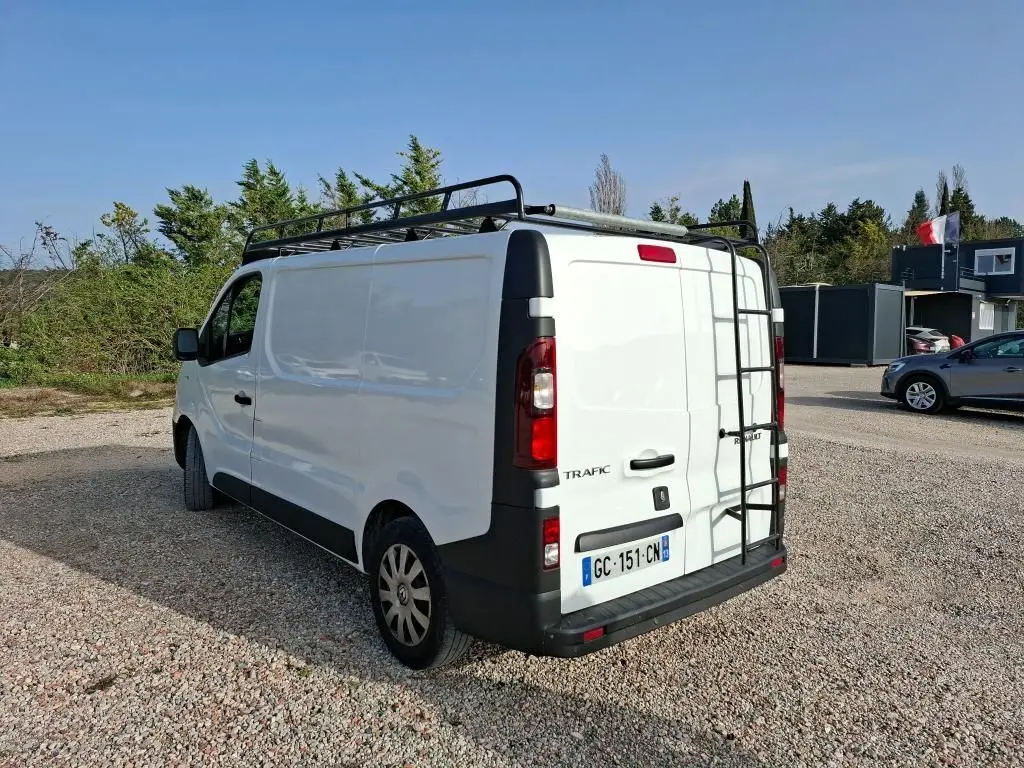 Vue 3/4 arrière droite du fourgon blanc Renault Trafic L1H1 2021 avec galerie et échelle noire sur toit.