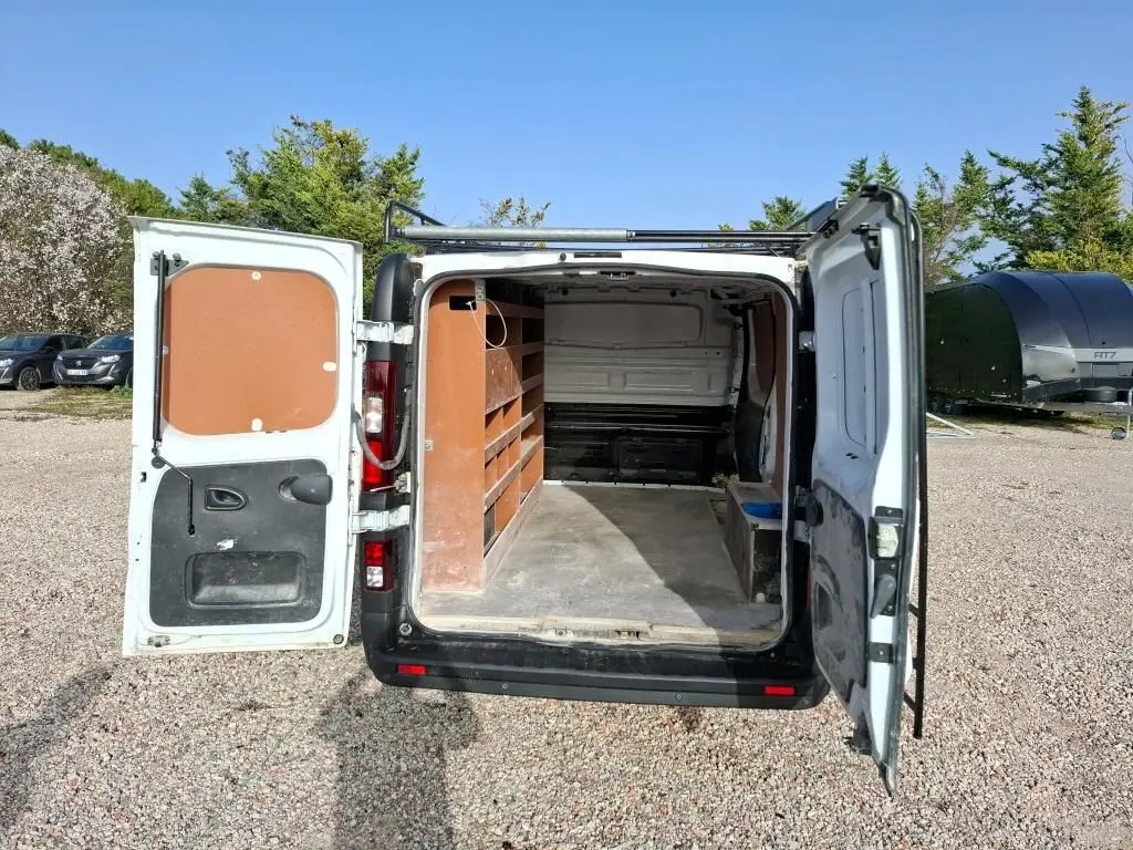 Vue arrière du Renault Trafic Fourgon blanc 2021 avec portes ouvertes montrant l'aménagement intérieur en bois.
