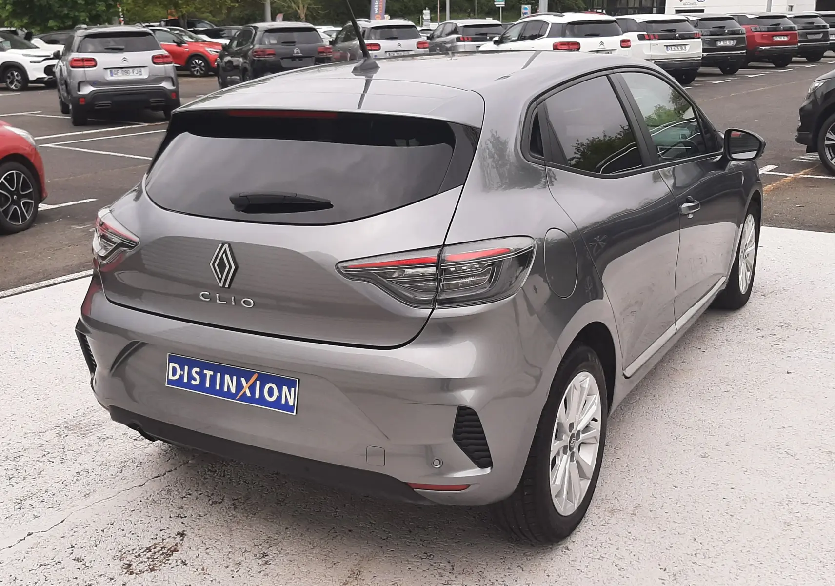 Vue 3/4 arrière droite d'une Renault Clio V gris schiste avec feux LED et vitres teintées, stationnée en extérieur.