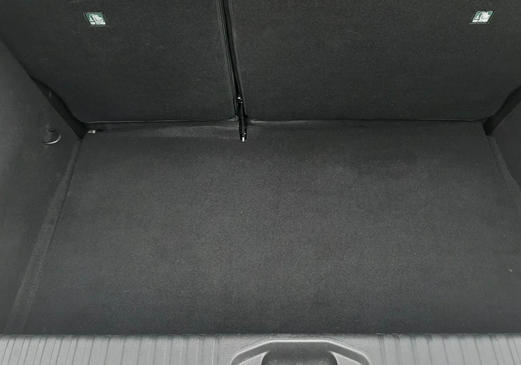 Coffre vide vu de dessus de la Renault Clio V gris schiste, montrant le revêtement intérieur noir et les dossiers arrière rabattables.