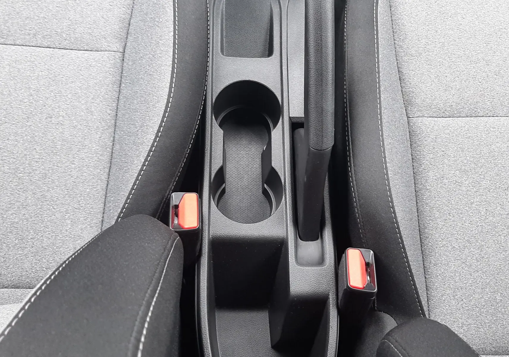 Vue plongeante sur la console centrale noire et les sièges tissu gris clair de la Renault Clio V 2025.