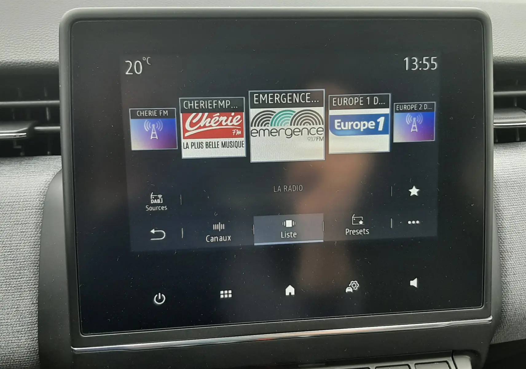 Écran tactile central de la Renault Clio V gris schiste, affichant les stations radio avec commandes en dessous.