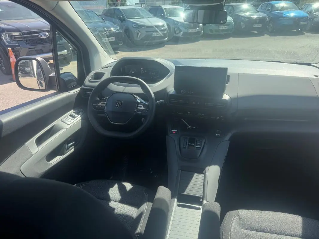 Vue intérieure avant du Peugeot Rifter gris 2026, montrant le volant multifonctions, l'écran tactile et la console centrale.