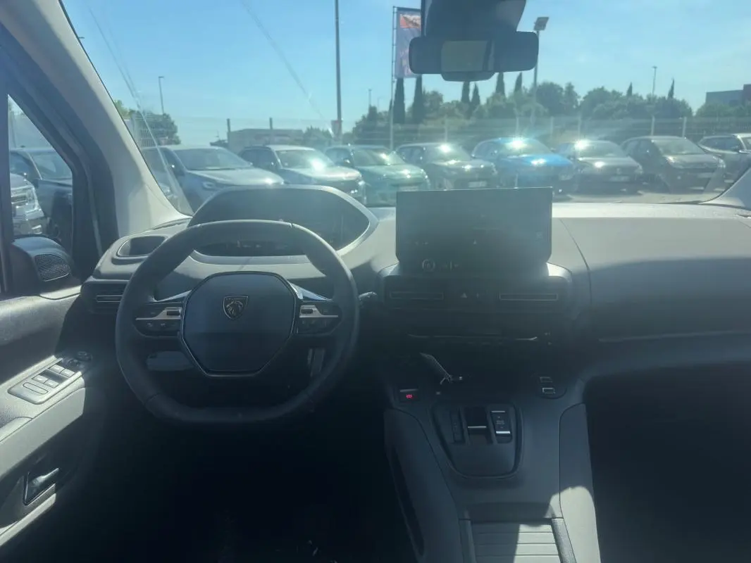 Vue intérieure du tableau de bord du Peugeot Rifter gris 2026, avec volant multifonctions et écran tactile central.