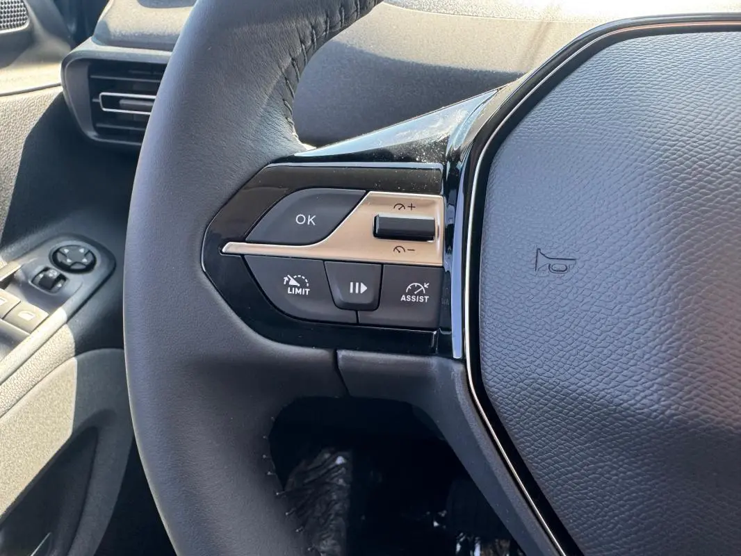 Gros plan sur le volant cuir gris du Peugeot Rifter 2026, avec commandes multifonctions et boutons de limitation de vitesse.