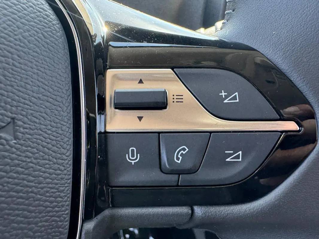 Gros plan sur les commandes multifonctions noires et dorées du volant cuir du Peugeot Rifter gris 2026.