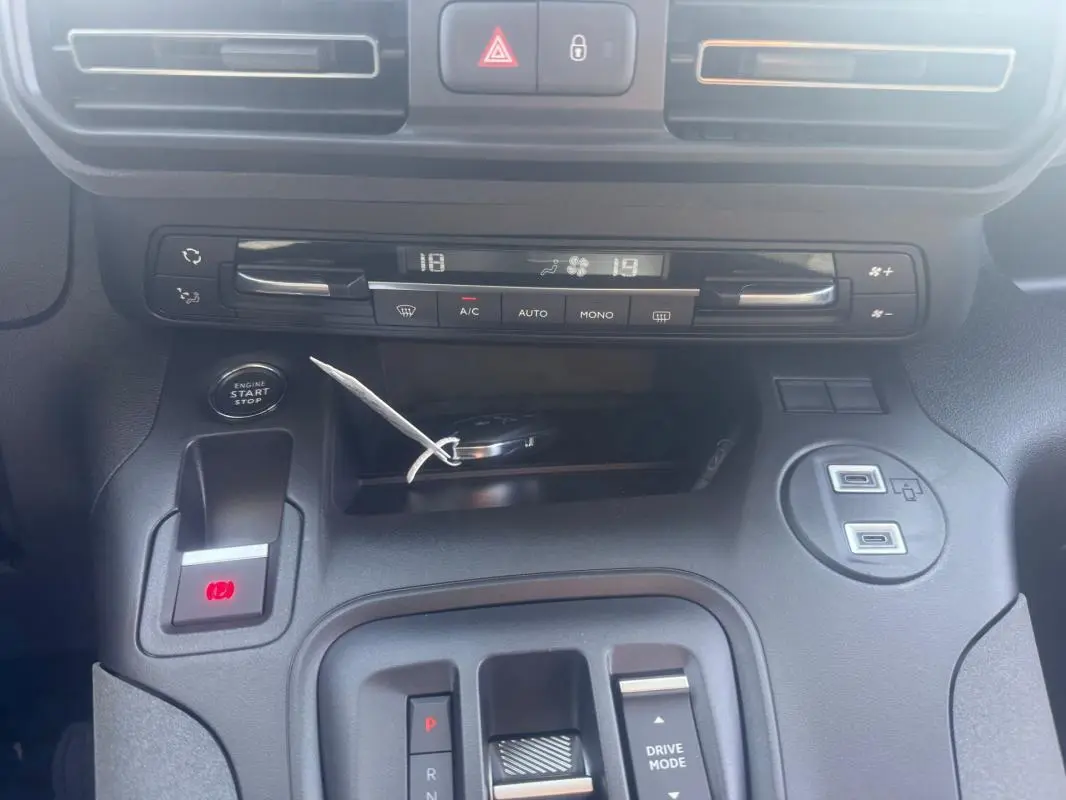 Vue rapprochée du tableau de bord et console centrale du Peugeot Rifter gris 2026, avec commandes climatisation et bouton start-stop.