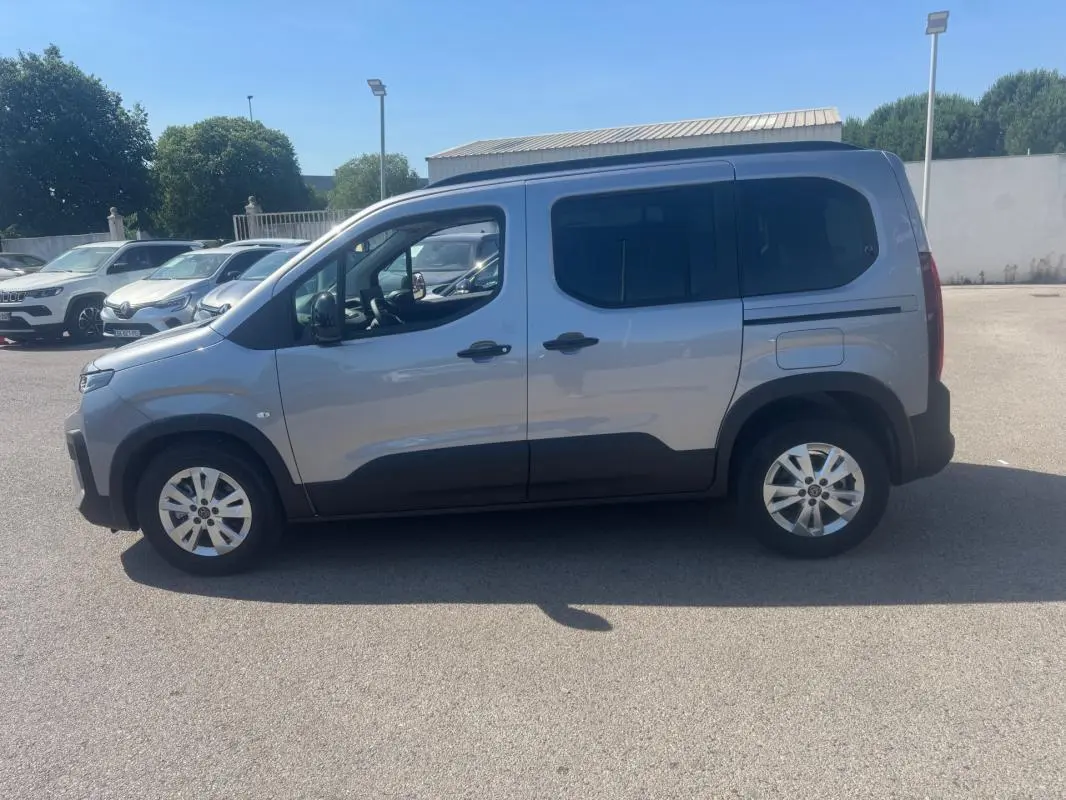 Peugeot Rifter gris vue de profil côté gauche, avec barres de toit et jantes alliage 17 pouces visibles.