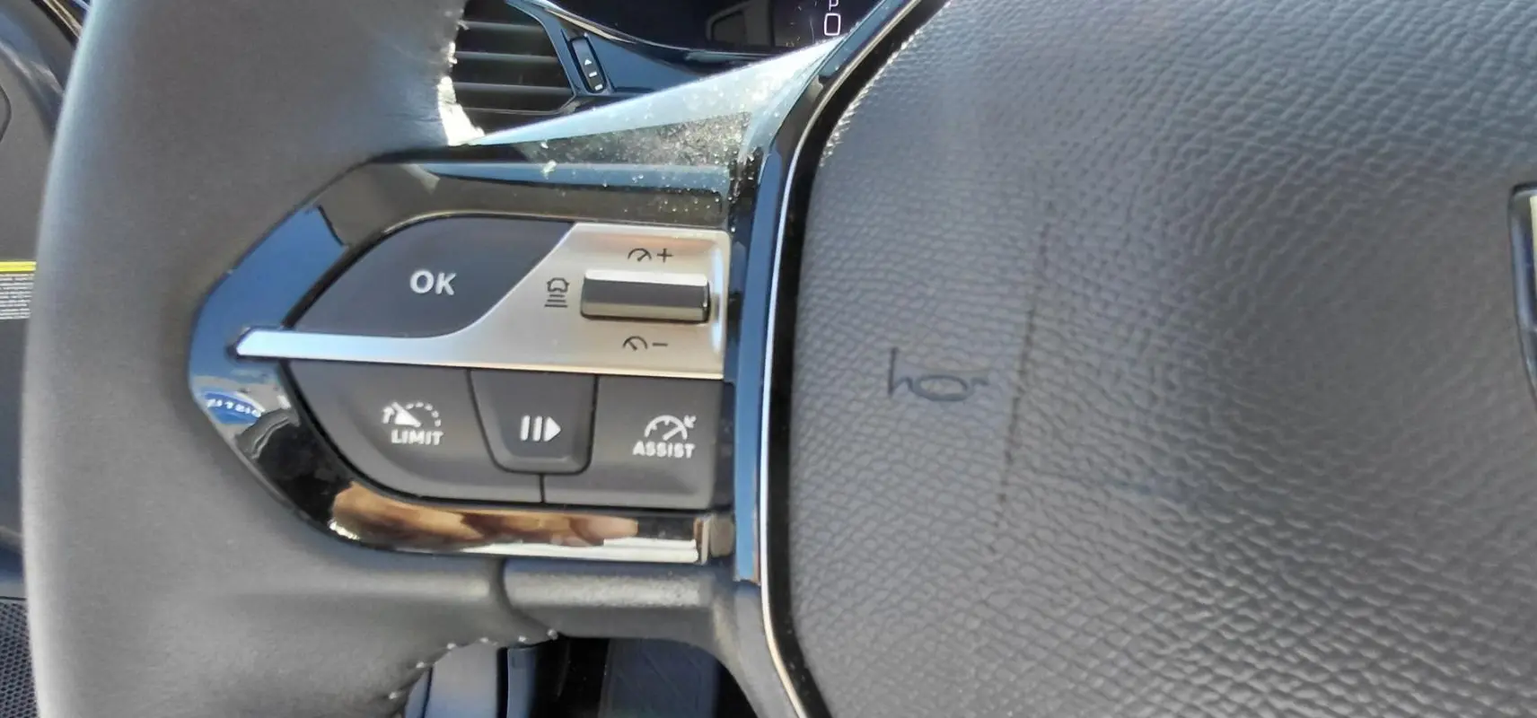 Détail des commandes à gauche du volant cuir noir du Peugeot 408 Hybrid 145 e-DCS6 Allure 2025.