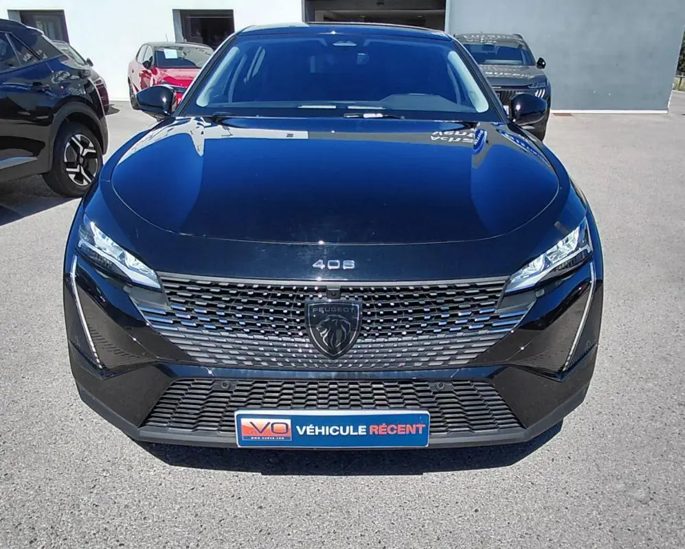 Vue avant d'une Peugeot 408 Hybrid 145 e-DCS6 Allure noire 2025 avec calandre distinctive et phares LED fins.