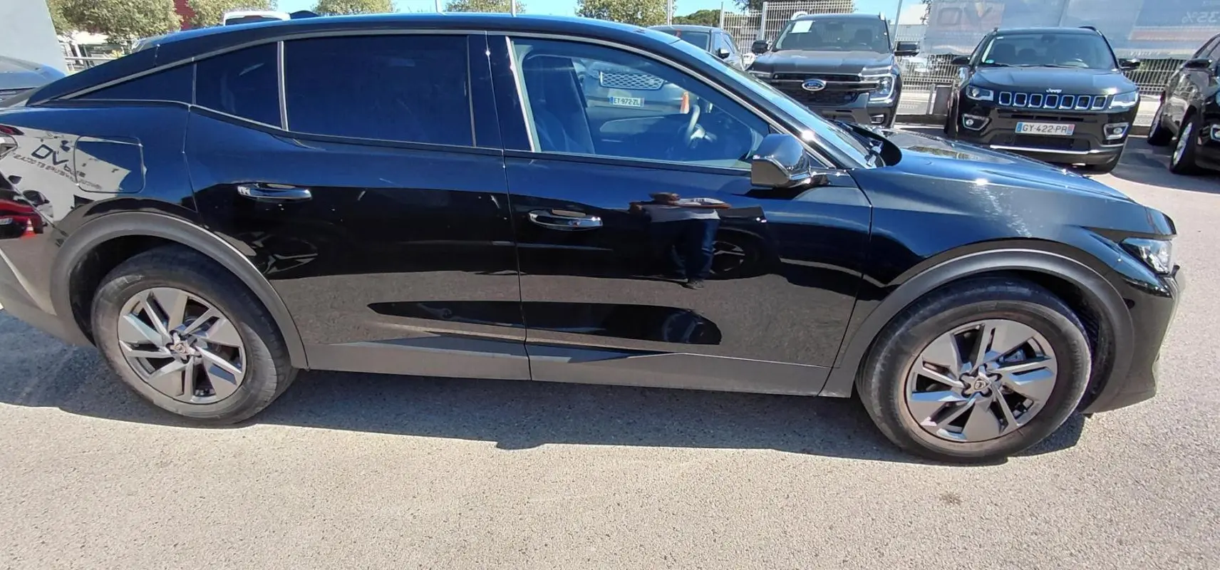 Vue de profil côté gauche d'une Peugeot 408 Hybrid 145 e-DCS6 Allure noire, soulignant ses jantes spécifiques et lignes fluides.