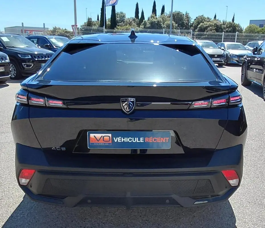 Vue arrière d'une Peugeot 408 noire 2025 avec feux LED distinctifs et logo lion central sur le hayon.