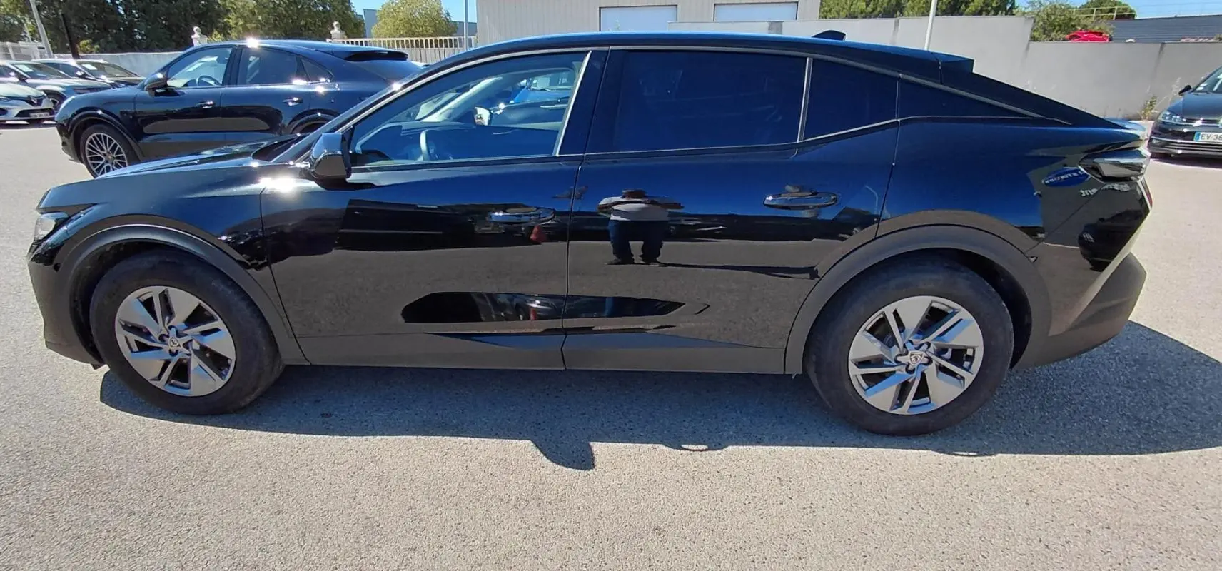 Profil côté gauche de la Peugeot 408 Hybrid 145 e-DCS6 Allure noire 2025 avec ses jantes distinctives en alliage.