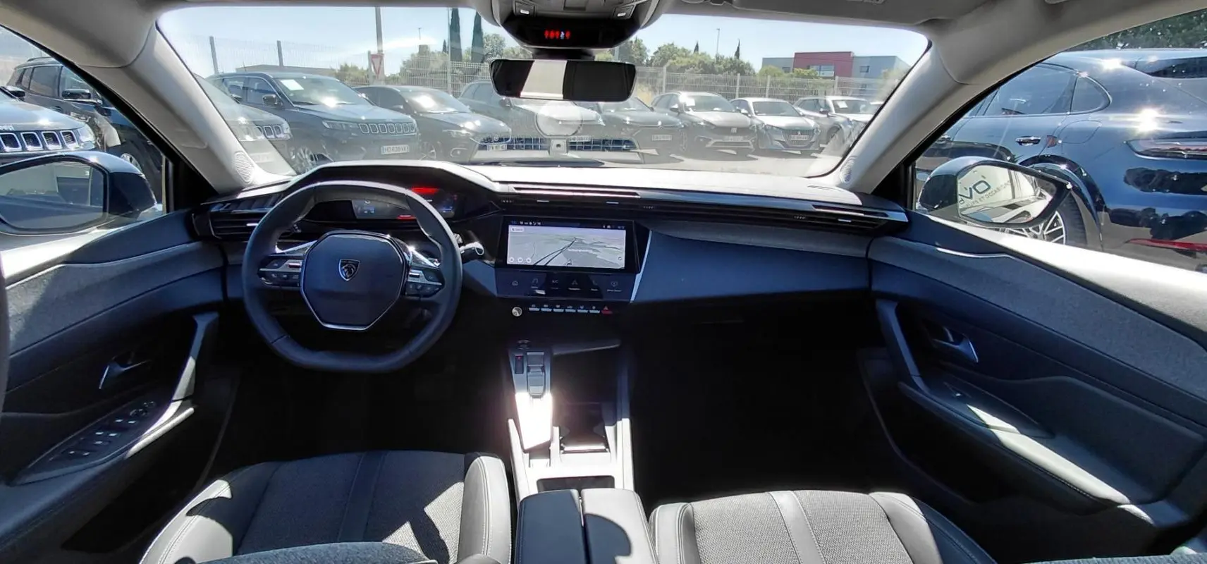 Vue intérieure avant du Peugeot 408 Hybrid 145 e-DCS6 Allure 2025 noir, avec tableau de bord numérique et écran central tactile.