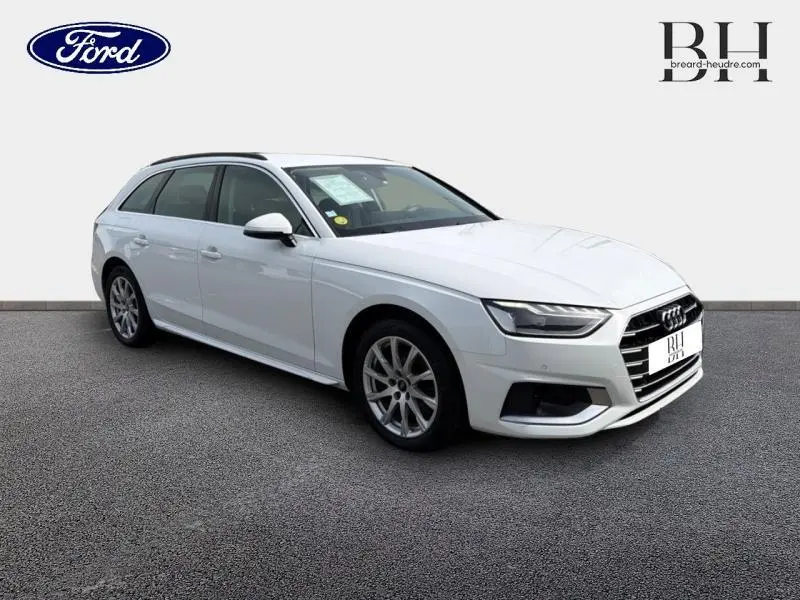 Audi A4 Avant blanc glacier métallisé vue 3/4 avant droit avec jantes alu et barres de toit visibles.