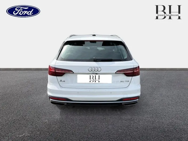 Vue arrière d'une Audi A4 Avant blanc glacier métallisé avec feux LED et double sortie d'échappement chromée.