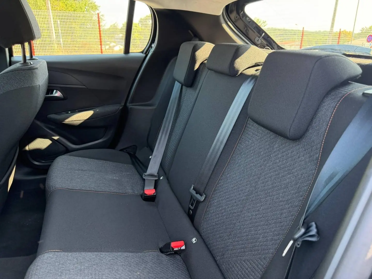 Vue intérieure de la banquette arrière noire avec surpiqûres orange de la Peugeot 208 1.2 100ch Style 2025.
