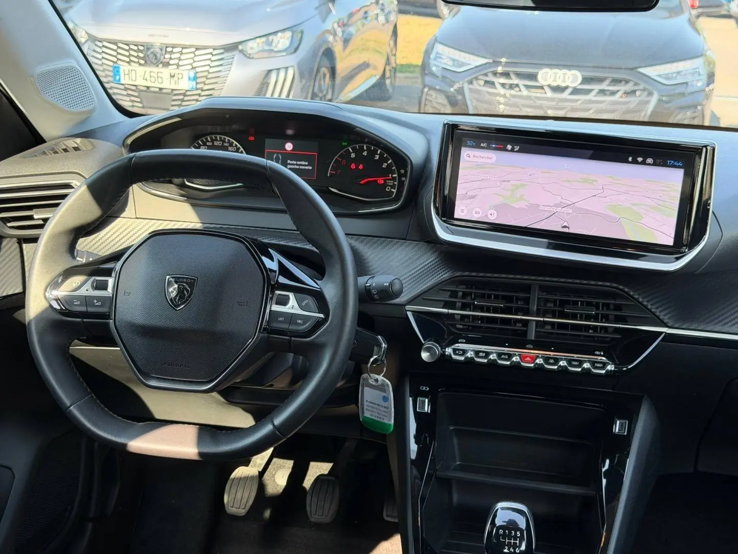 Intérieur de la Peugeot 208 noir Perla Nera, vue du poste de conduite avec tableau de bord et écran tactile central.