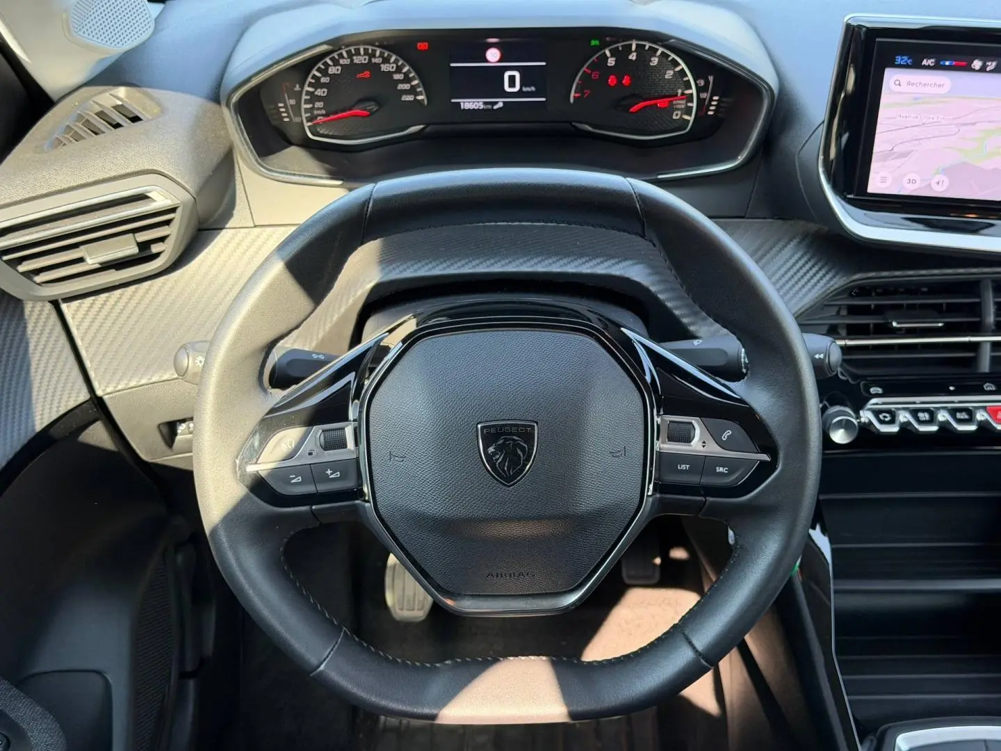 Vue rapprochée du volant noir de la Peugeot 208 1.2 100ch Style 2025, avec tableau de bord digital et écran tactile latéral.