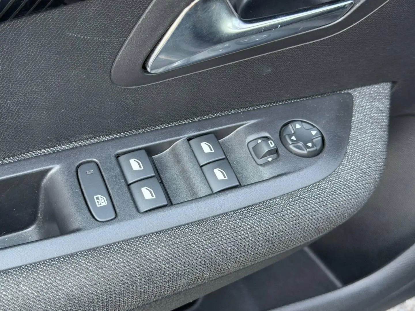 Détail des commandes de lève-vitres et rétroviseurs sur la porte côté conducteur d'une Peugeot 208 Noir Perla Nera.