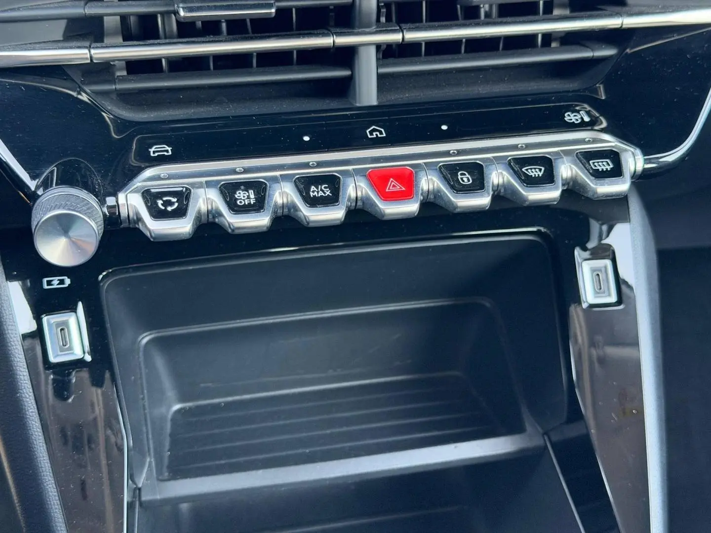 Gros plan sur la console centrale de la Peugeot 208 1.2 100ch Style 2025, boutons argentés et noir laqué.