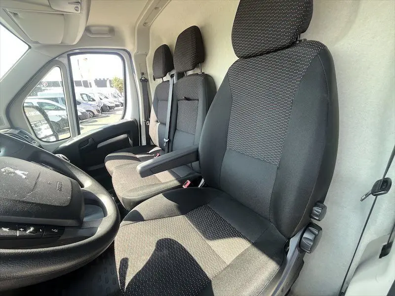 Vue intérieure côté conducteur du Peugeot Boxer FGN blanc 2021, montrant les sièges avant en tissu noir à motifs discrets.