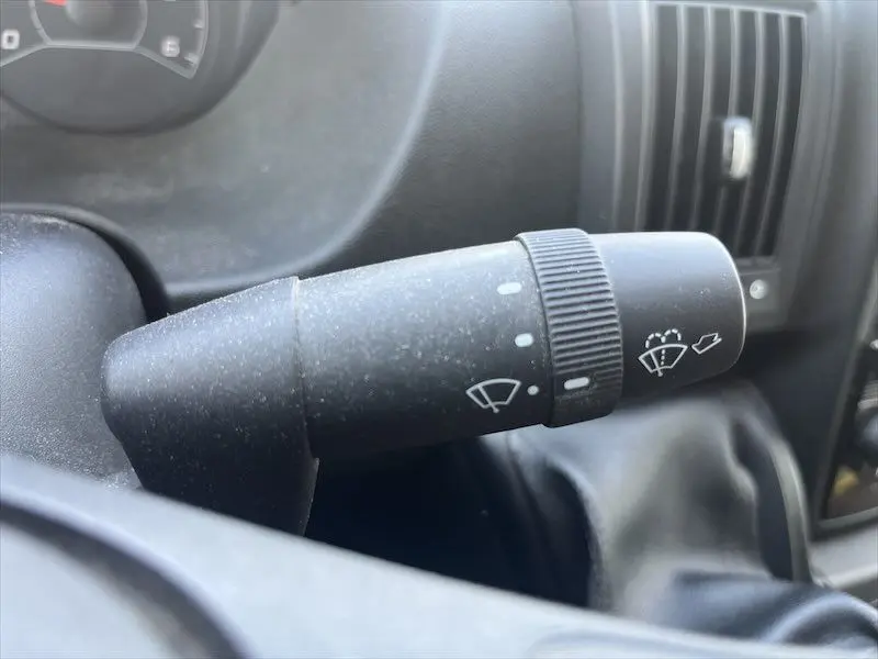 Gros plan sur le commodo d'essuie-glace noir dans l'habitacle du Peugeot Boxer FGN blanc, côté conducteur.