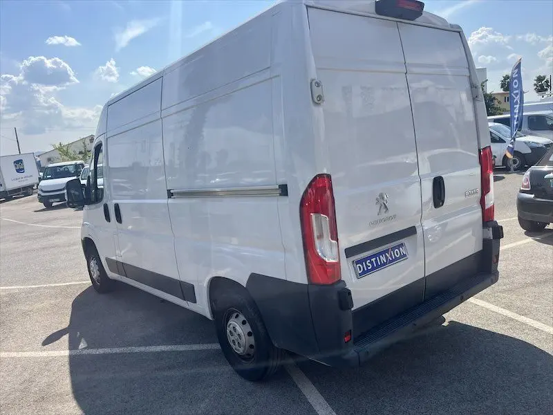 Vue 3/4 arrière droite d’un utilitaire Peugeot Boxer blanc avec portes latérales et logo Distinxion visible sur parking.
