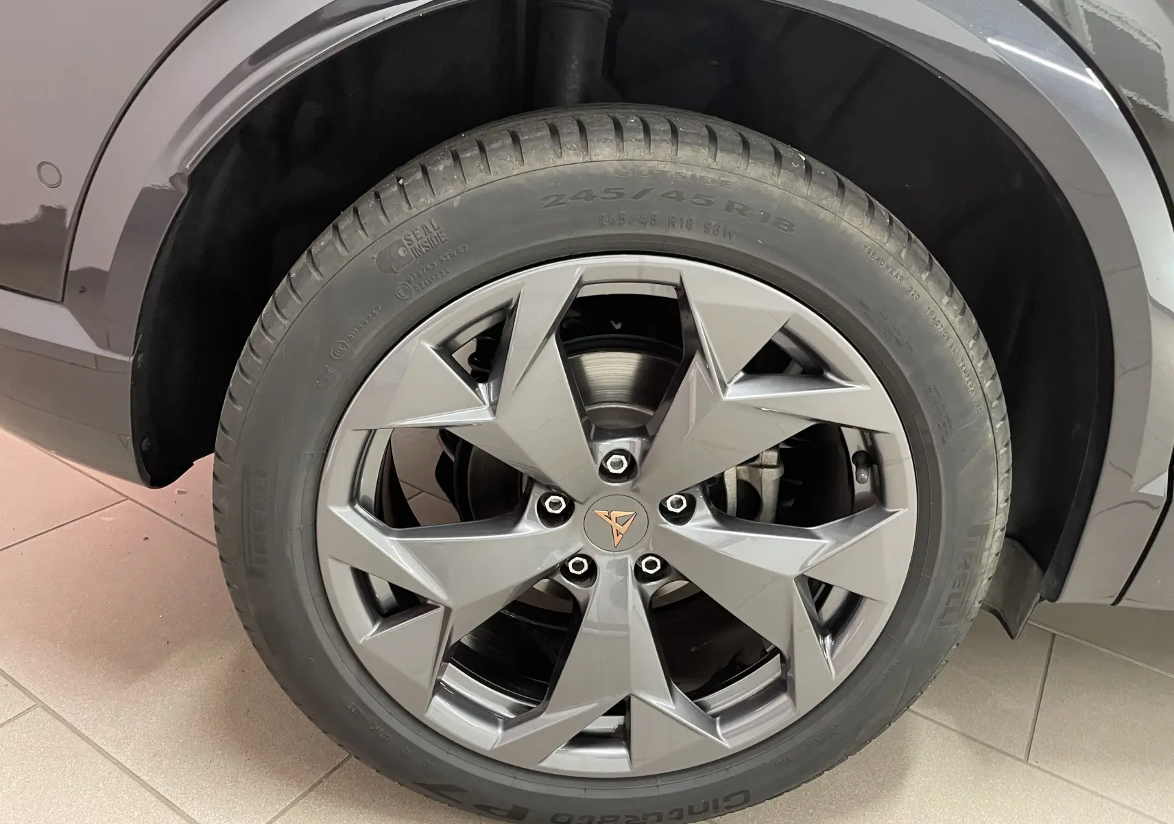 Gros plan sur la roue avant droite du CUPRA Formentor noir minuit, mettant en valeur la jante au design anguleux et le logo central.